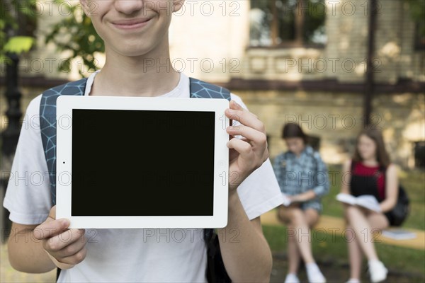 Close up highschool boy holding tablet hands
