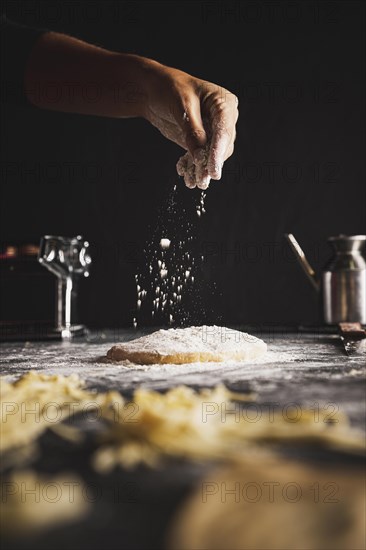 Close up person sprinkling flour dough