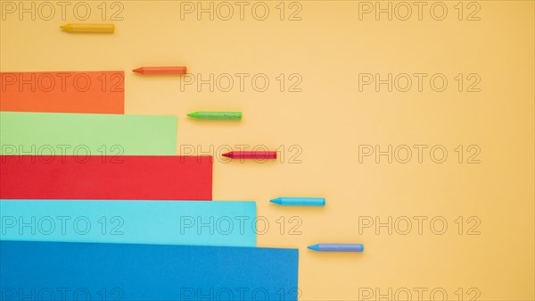 Colorful crayon craft paper arranged yellow surface