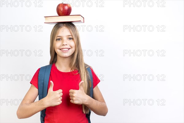 Confident schoolgirl balancing book head