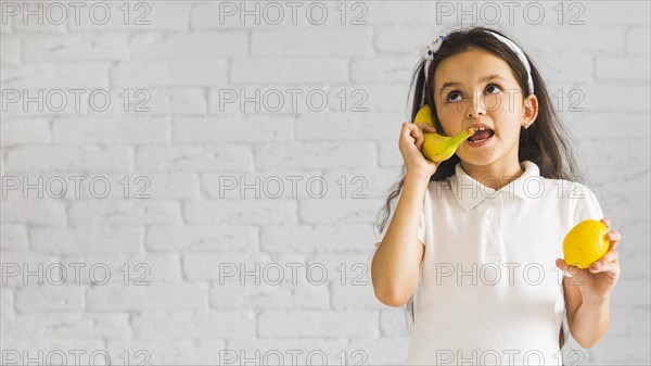 Crazy girl holding lemon her hand making fun with yellow banana