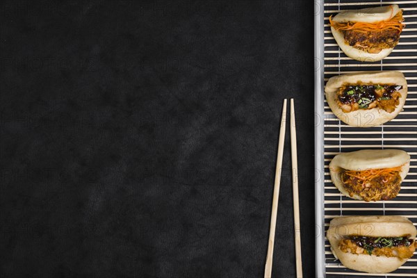 Different types gua bao placemat with chopsticks against black textured backdrop