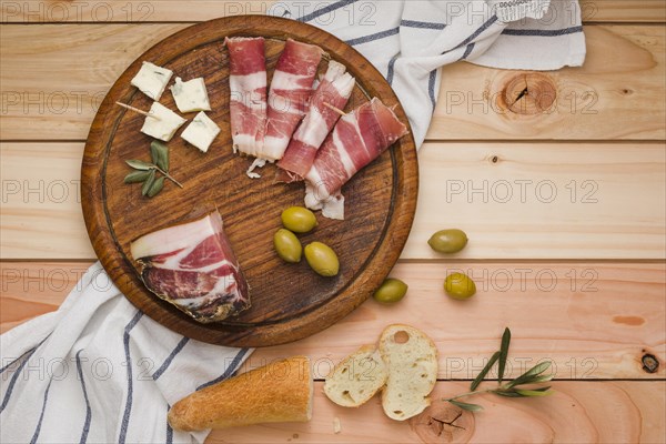 Elevated view bacon olives cheese bread slices wooden circular board table