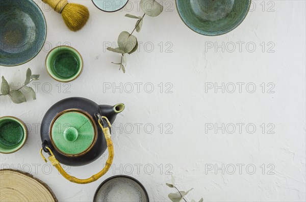 Elevated view teapot bowl tea cup brush isolated white backdrop