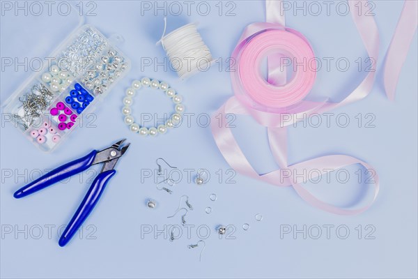 Equipment making hand made earrings with pink ribbon blue background