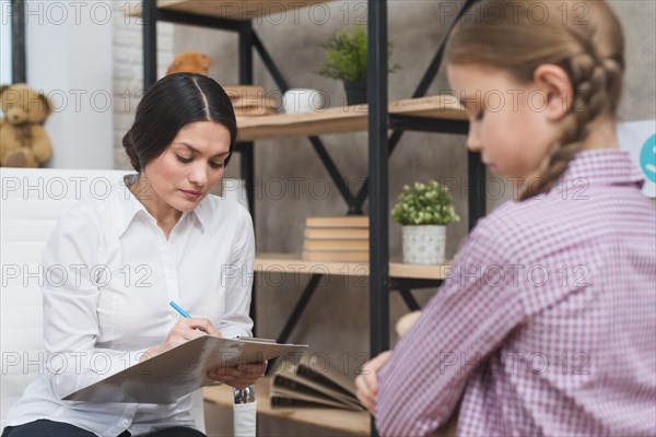 Female psychologist taking notes clipboard therapy session