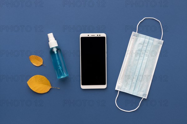 Flat lay medical mask with smartphone hand sanitizer