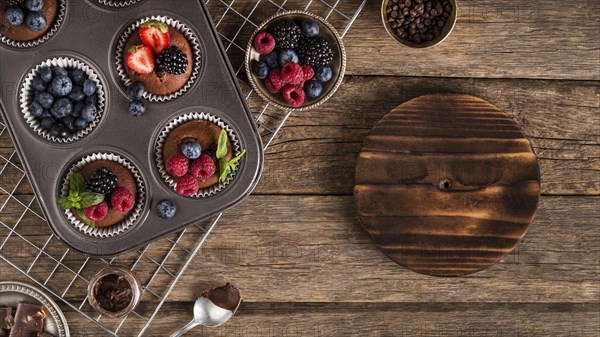 Flat lay tasty muffin with forest fruit baking tray