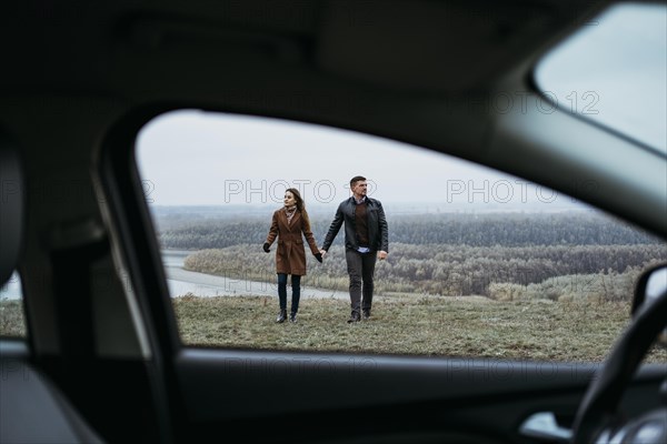 Front view couple holding hands from inside car