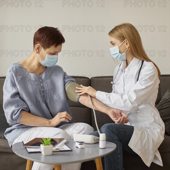 Front view covid recovery center female doctor with medical mask checking elder patient s blood pressure