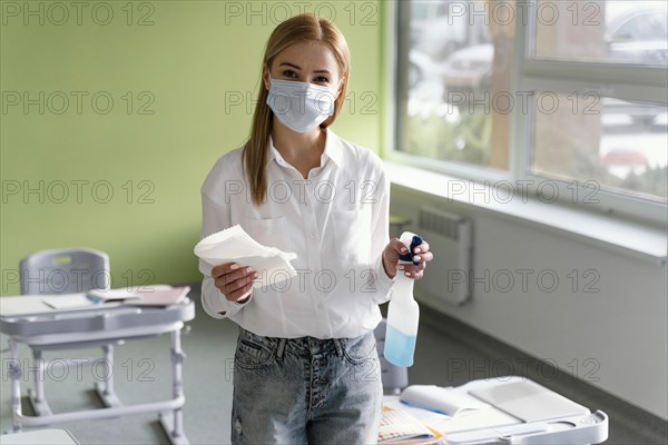 Front view female teacher with disinfecting solution classroom