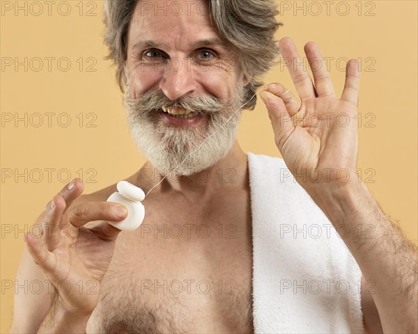 Front view senior bearded man with dental floss