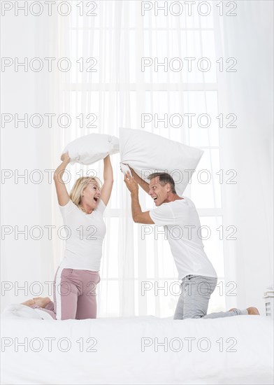 Full shot couple having pillow fight