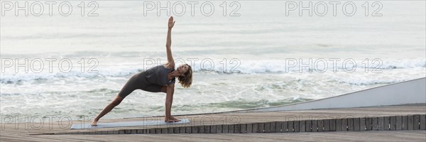 Full shot woman doing triangle pose beach