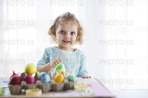 Girl coloring eggs looking camera