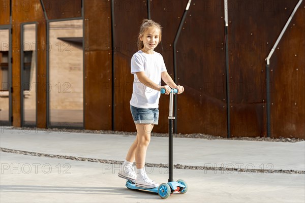 Girl white t shirt riding blue scooter