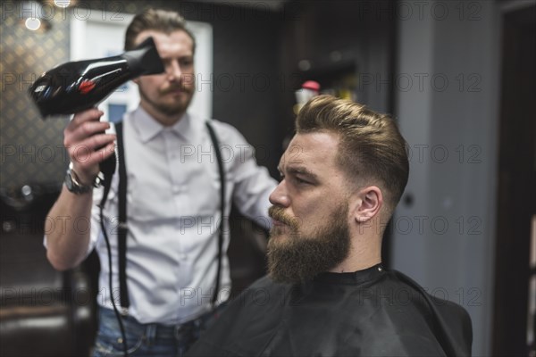Hairdresser using drier hair client