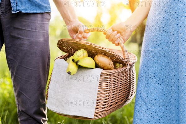 Hands couple holding picnic basket full food