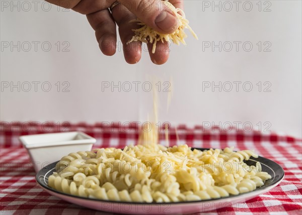 Hand sprinkling cheese pasta