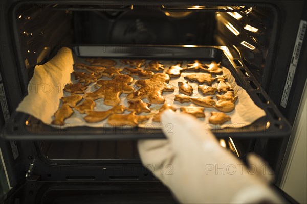 Hand taking dripping pan from oven