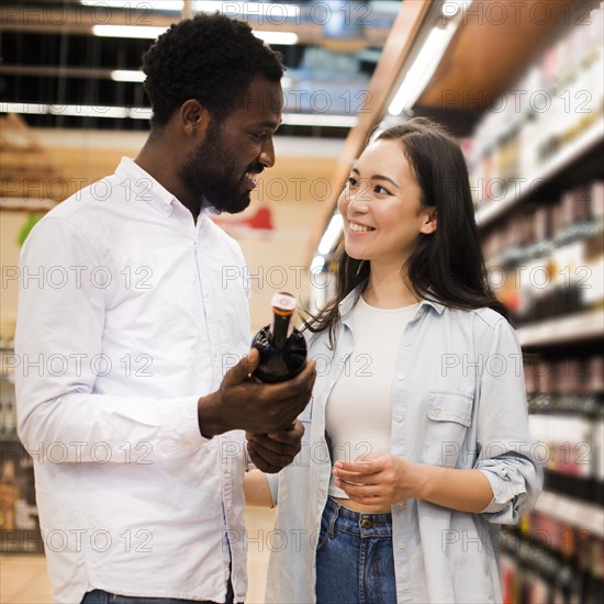 Happy couple choosing wine grocery store