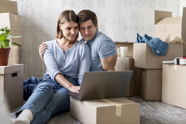 Happy couple home with boxes laptop ready move out