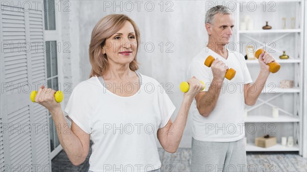 Happy senior couple exercising using dumbbells