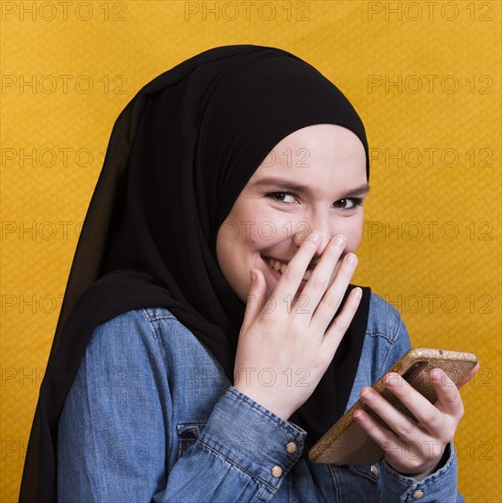 Happy woman wearing denim shirt using smartphone bright background