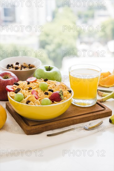 Healthy breakfast with cornflakes dried fruits apple juice glass table