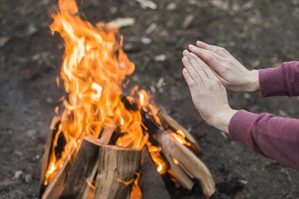 High angle woman warming bonfire