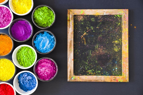 Holi color powder bowls near small slate black background