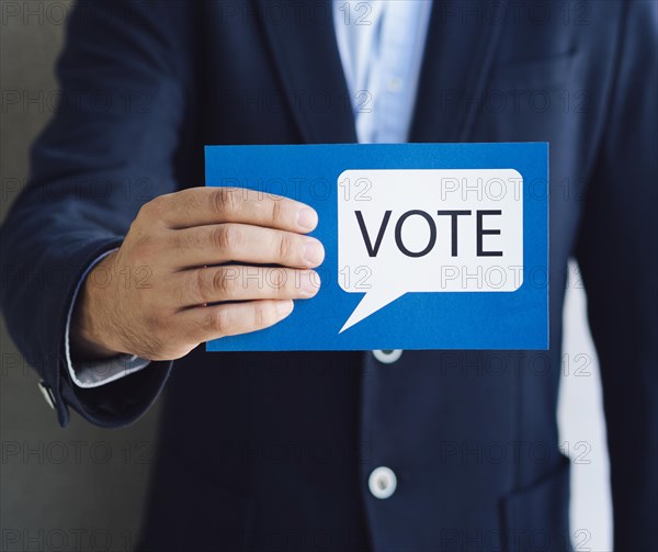 Medium shot man showing voting card with speech bubble