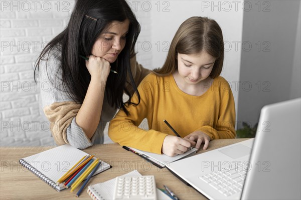 Medium shot woman looking girl writing