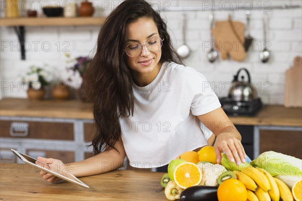 Medium shot woman with fruits tablet