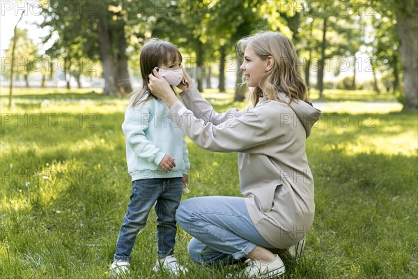 Mom putting her daughter s medical mask