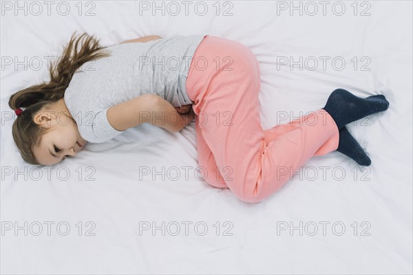 Overhead view girl lying bed suffering from stomach ache