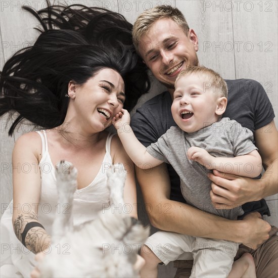 Overhead view happy couple playing with dog their son lying hardwood floor