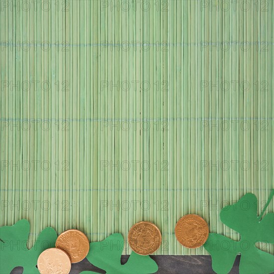 Paper clovers near coins bamboo mat