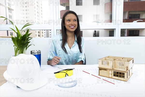 Pensive african american lady chair near safety helmet model house table