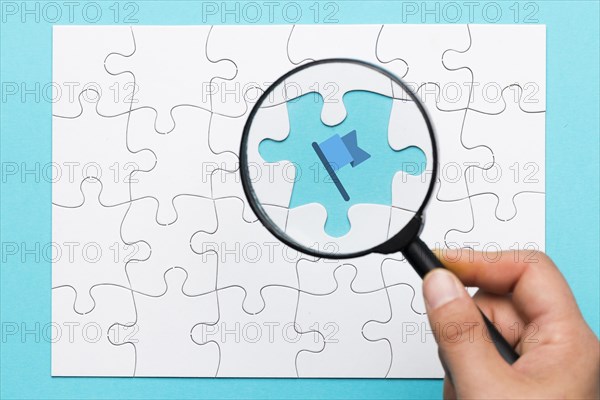 Person s hand holding magnifying glass flag icon blue backdrop
