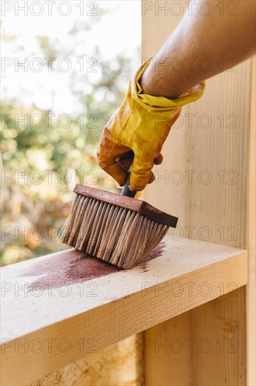 Person varnishing piece wood from house construction