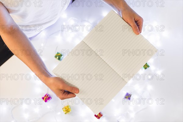 Person with writing book near gifts fairy lights