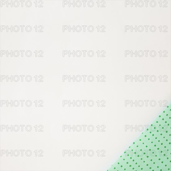 Polka dot green wrapped paper corner white background