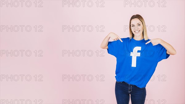 Portrait happy young woman pointing her t shirt with facebook icon