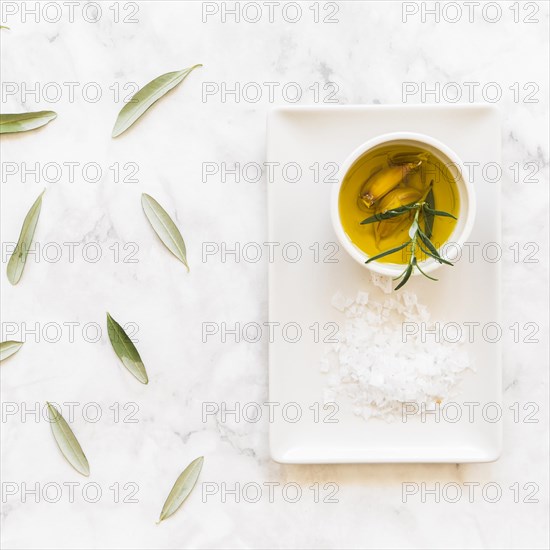 Rosemary garlic cloves oil bowl with salt white tray