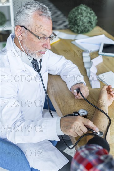 Serious doctor measuring blood pressure patient