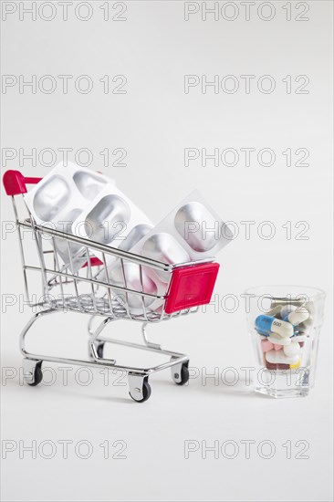 Shopping cart with pill blister medicines glass white background