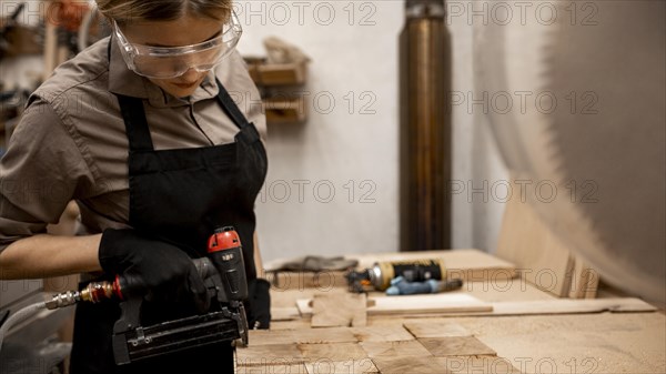 Side view female carpenter with pneumatic stapler