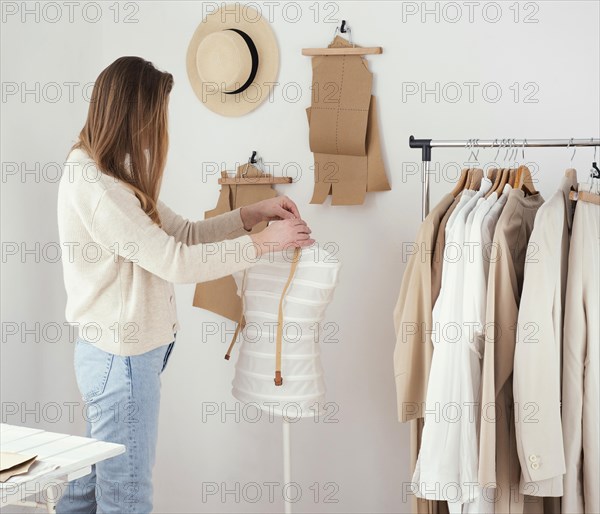 Side view female tailor studio with clothes