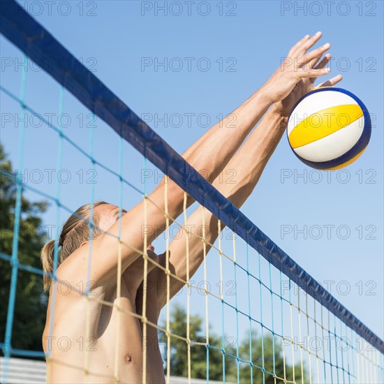 Side view shirtless man net playing beach volleyball